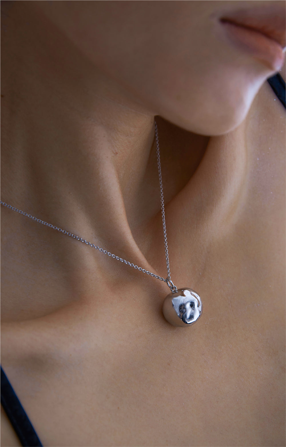 Silver pendant necklace with an abstract red dust design on a delicate chain.